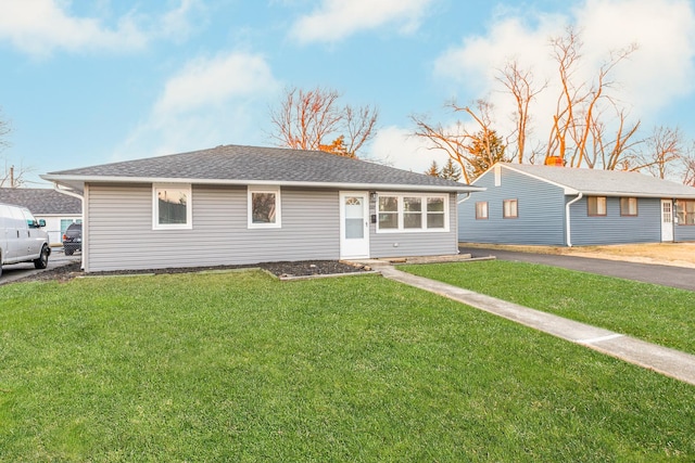 ranch-style home with a shingled roof and a front yard