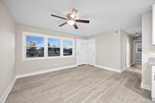 unfurnished living room with baseboards, ceiling fan, and light wood-type flooring