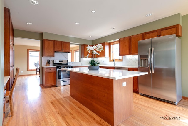 kitchen with appliances with stainless steel finishes, a kitchen island, light countertops, and a wealth of natural light