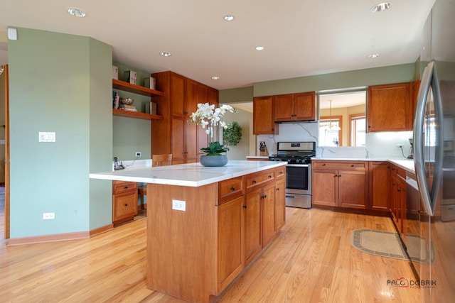 kitchen with light countertops, stainless steel gas range oven, light wood finished floors, and a kitchen island