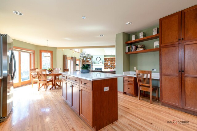 kitchen featuring light wood-type flooring, a kitchen island, light countertops, and stainless steel refrigerator with ice dispenser