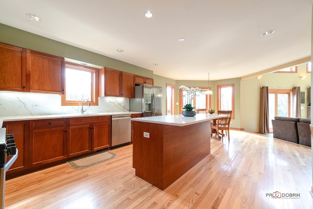 kitchen featuring stainless steel appliances, plenty of natural light, brown cabinetry, and a sink