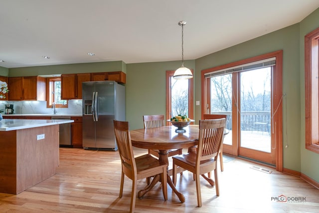 dining area with light wood-type flooring, baseboards, and visible vents