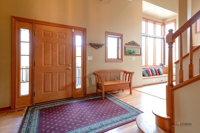 foyer entrance featuring visible vents, baseboards, stairway, and wood finished floors