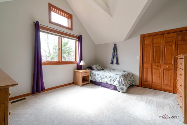 bedroom featuring visible vents, multiple windows, vaulted ceiling, and light carpet