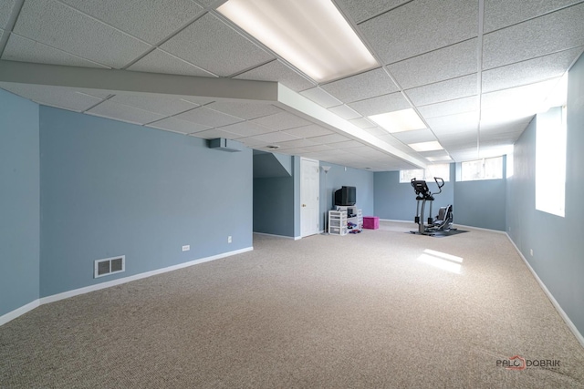 basement featuring a drop ceiling, baseboards, carpet, and visible vents