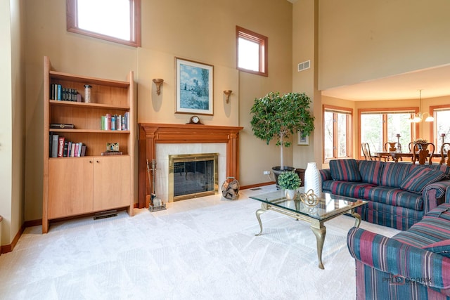 living area featuring a wealth of natural light, a fireplace, a towering ceiling, and visible vents