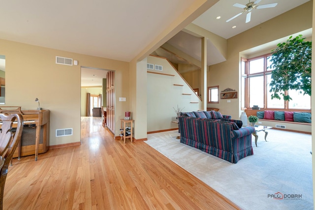 living room featuring visible vents, ceiling fan, baseboards, and wood finished floors