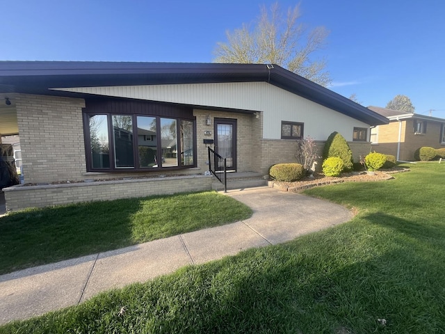 view of exterior entry with a lawn and brick siding