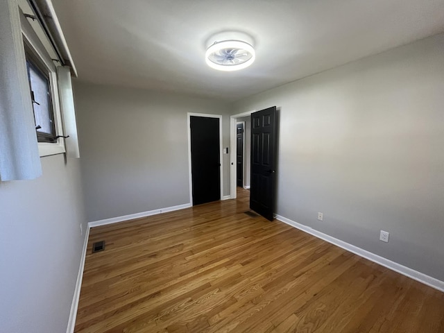 unfurnished room with baseboards and wood finished floors