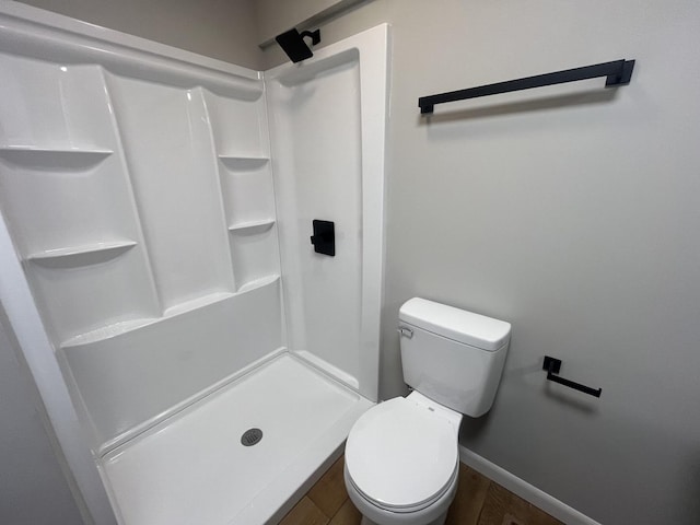 full bath featuring wood finished floors, a stall shower, toilet, and baseboards
