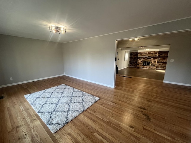 empty room with baseboards, wood finished floors, and a fireplace