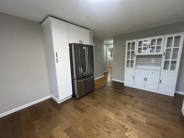 kitchen with stainless steel fridge with ice dispenser, dark wood finished floors, white cabinets, and baseboards