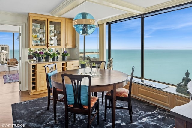 dining area with dark wood finished floors, a water view, ornamental molding, and expansive windows