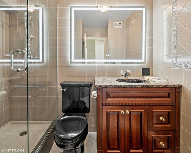 bathroom with tile walls, a shower stall, and vanity