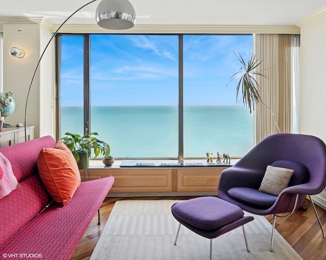 sitting room with ornamental molding, wood finished floors, and a water view