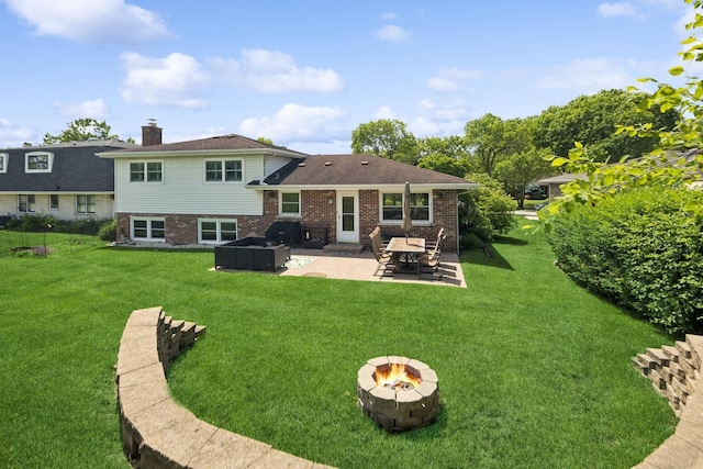 rear view of house with brick siding, a patio, a yard, and an outdoor fire pit