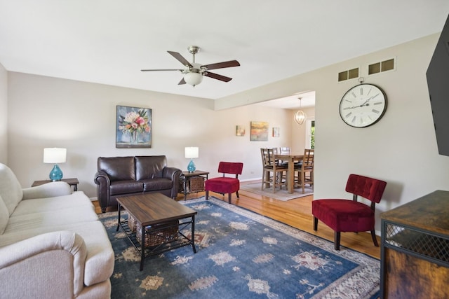 living area featuring baseboards, ceiling fan, and wood finished floors