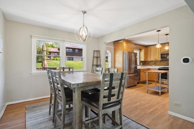 dining room featuring baseboards, light wood-style flooring, and a notable chandelier