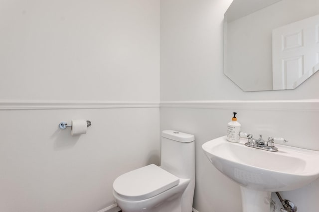 half bath featuring toilet and a sink