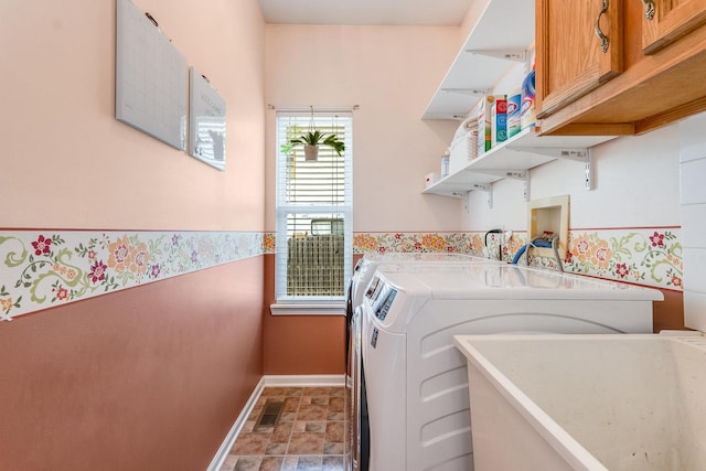 washroom featuring visible vents, baseboards, cabinet space, washing machine and clothes dryer, and stone finish flooring
