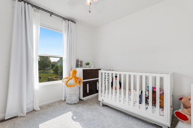 bedroom with a crib, baseboards, multiple windows, and carpet