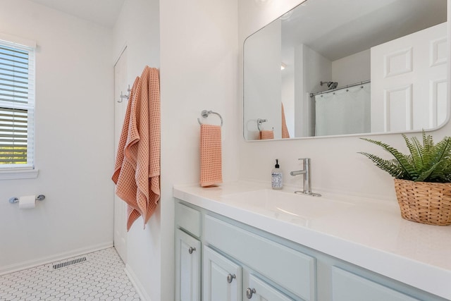 full bath featuring vanity, baseboards, and visible vents