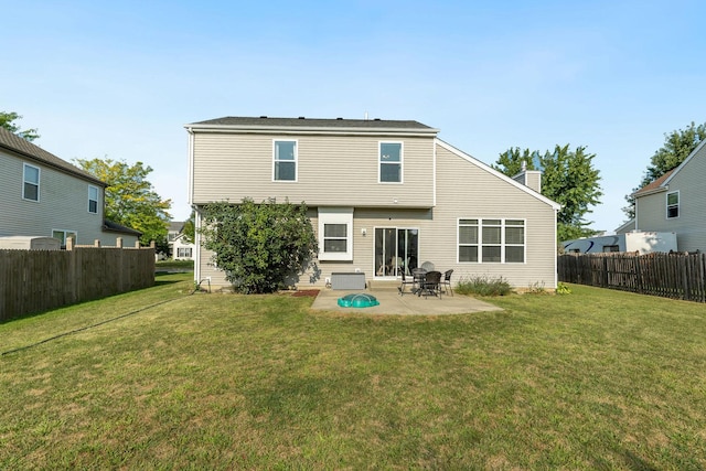 rear view of property featuring a yard, a fenced backyard, a patio, and a chimney