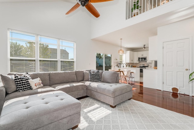 living room featuring light wood finished floors, a towering ceiling, and ceiling fan