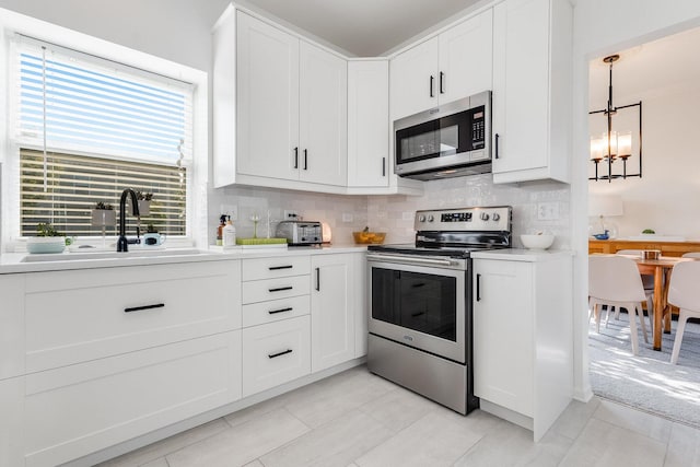 kitchen featuring decorative backsplash, appliances with stainless steel finishes, an inviting chandelier, and a sink