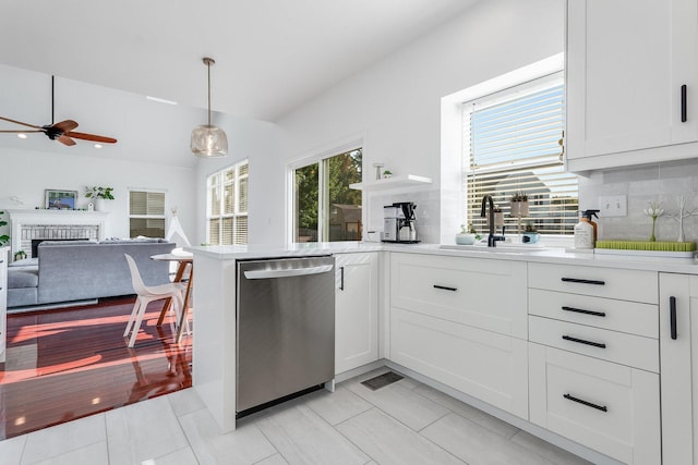 kitchen with ceiling fan, stainless steel dishwasher, light countertops, a sink, and backsplash