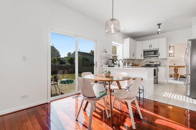 dining area featuring light wood-style flooring, baseboards, and visible vents