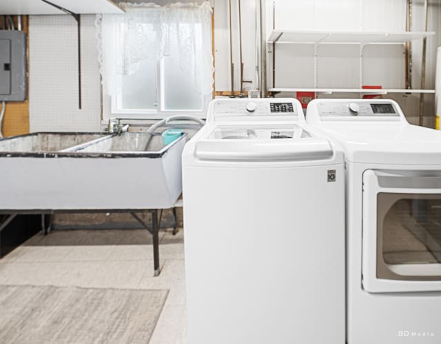 washroom featuring a sink, washing machine and dryer, laundry area, and electric panel