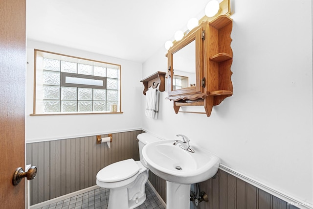 bathroom with toilet, tile patterned floors, wood walls, and a wainscoted wall