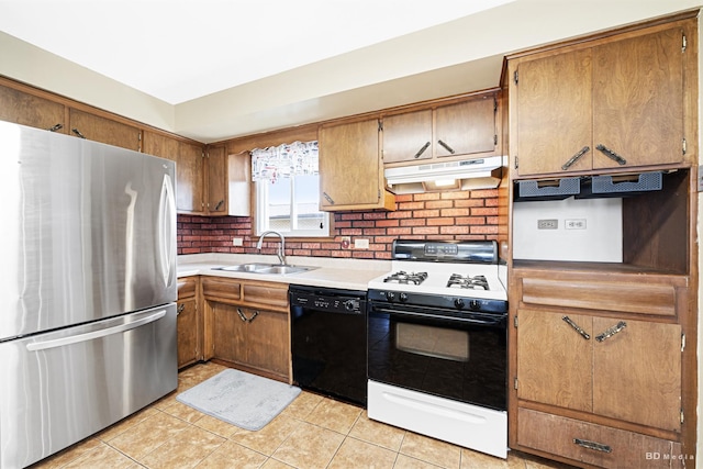 kitchen with black dishwasher, a sink, freestanding refrigerator, under cabinet range hood, and gas range oven