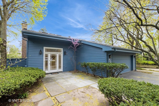 349 Ridge Rd, Kenilworth, IL 60043 - back of house with aphalt driveway, a garage, and a chimney