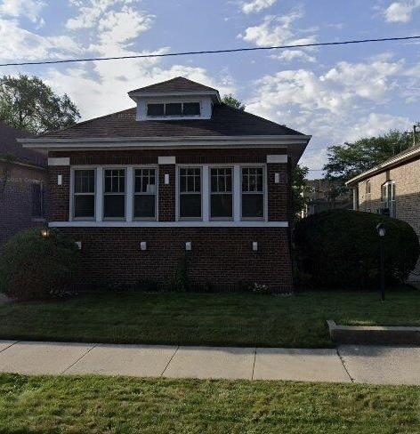 bungalow with a front lawn and brick siding