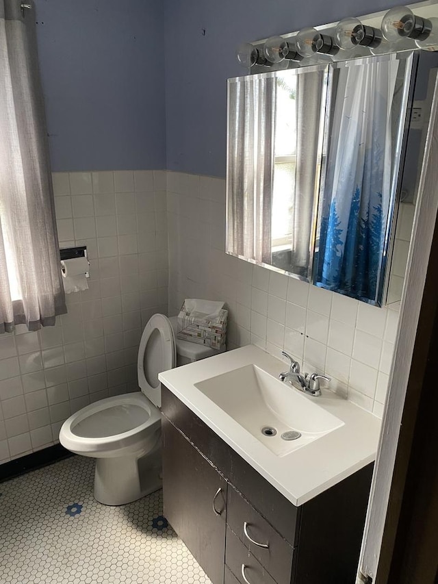 bathroom with tile walls, toilet, tile patterned flooring, and vanity