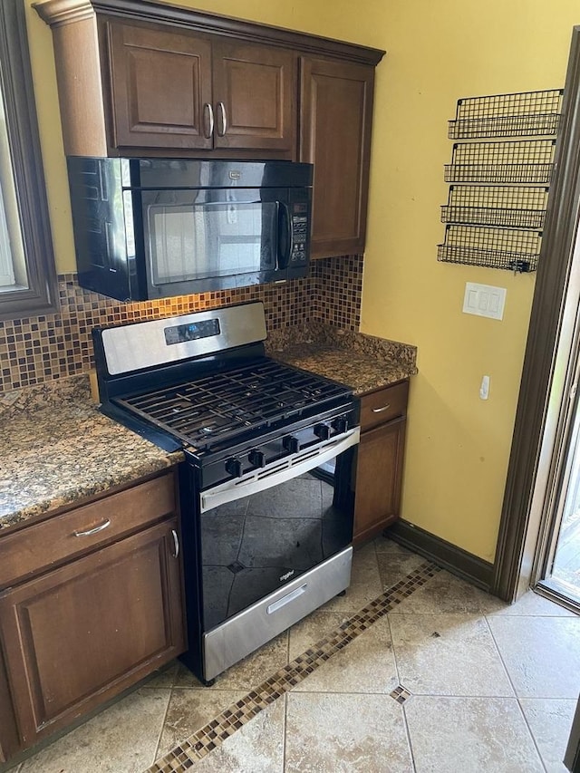 kitchen featuring decorative backsplash, gas range, baseboards, and black microwave