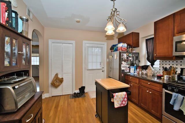 6237 N Mozart St, Chicago, IL 60659 - kitchen with light wood finished floors, dark countertops, tasteful backsplash, and appliances with stainless steel finishes
