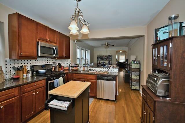 6237 N Mozart St, Chicago, IL 60659 - kitchen featuring tasteful backsplash, ceiling fan, appliances with stainless steel finishes, a peninsula, and light wood-style flooring