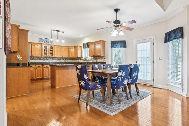 dining room with baseboards, light wood-style floors, ceiling fan, and ornamental molding