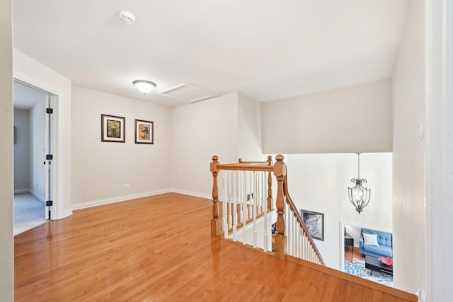 hallway with attic access, baseboards, wood finished floors, and an upstairs landing