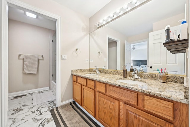 ensuite bathroom featuring marble finish floor, double vanity, ceiling fan, and a sink