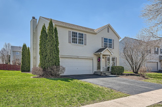 traditional-style home with fence, a front lawn, an attached garage, a chimney, and driveway