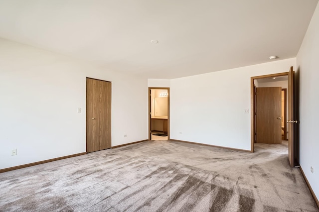 unfurnished bedroom featuring ensuite bathroom, baseboards, and carpet floors