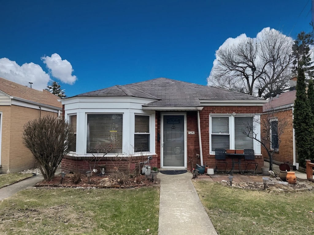 bungalow-style house with brick siding and a shingled roof