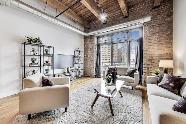 living area with a towering ceiling, brick wall, beamed ceiling, wooden ceiling, and wood finished floors