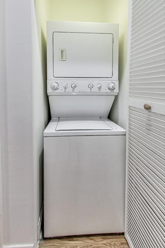 laundry area featuring light wood-style flooring, stacked washer / dryer, and laundry area
