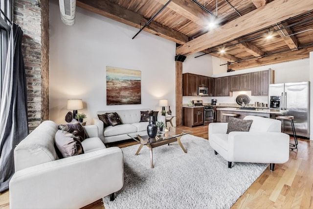 living area with a high ceiling, light wood-style floors, wood ceiling, and beamed ceiling